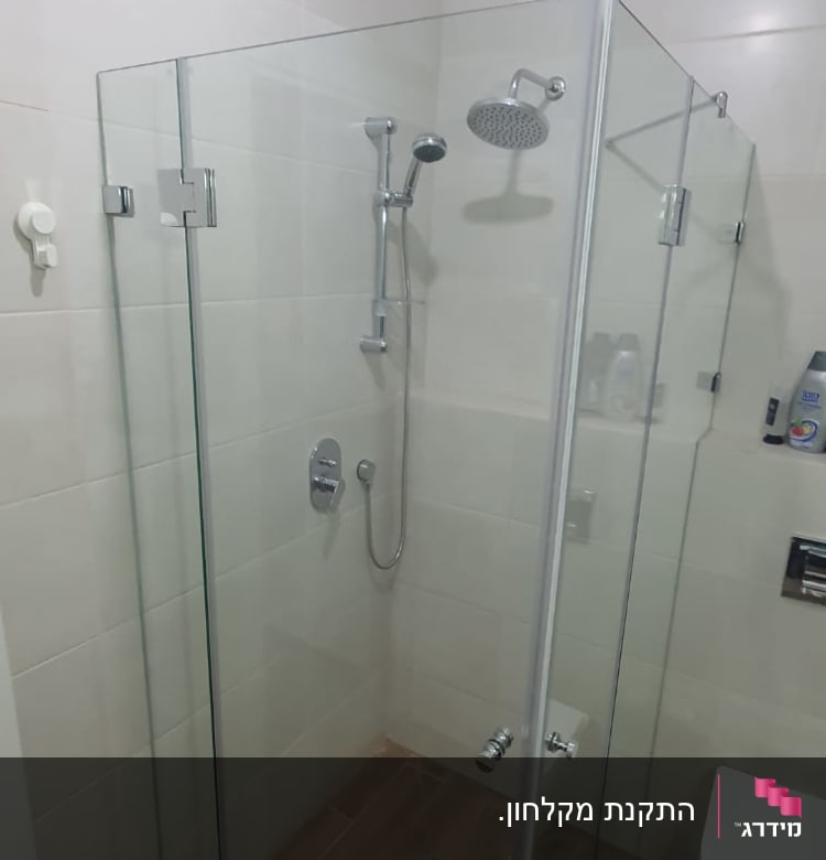 מקלחון זכוכית עם ראש מקלחת וכמה בקבוקי סבון